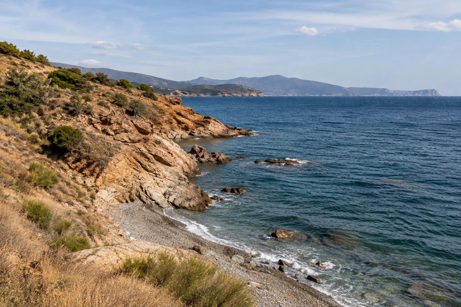 Vue côtière méditerranéenne, crique de galets et rochers au bord de l’eau